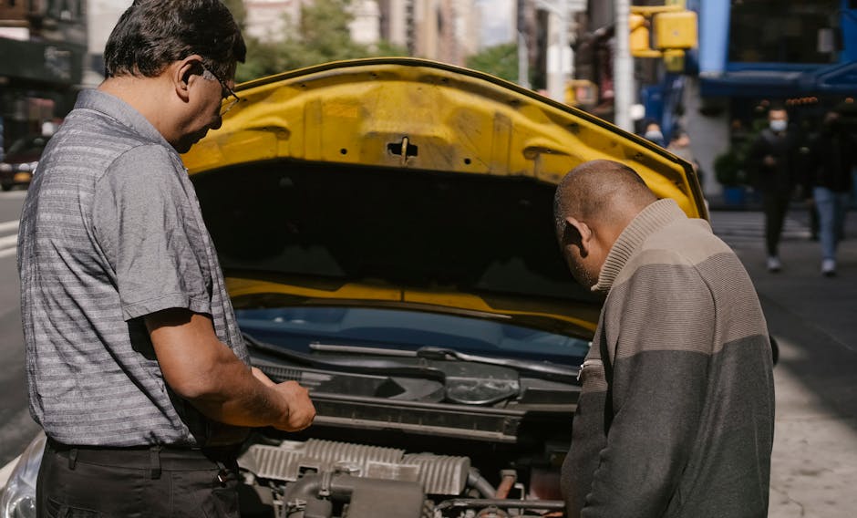 Back view of ethnic man identifying problems in engine system of car under hood standing near driver